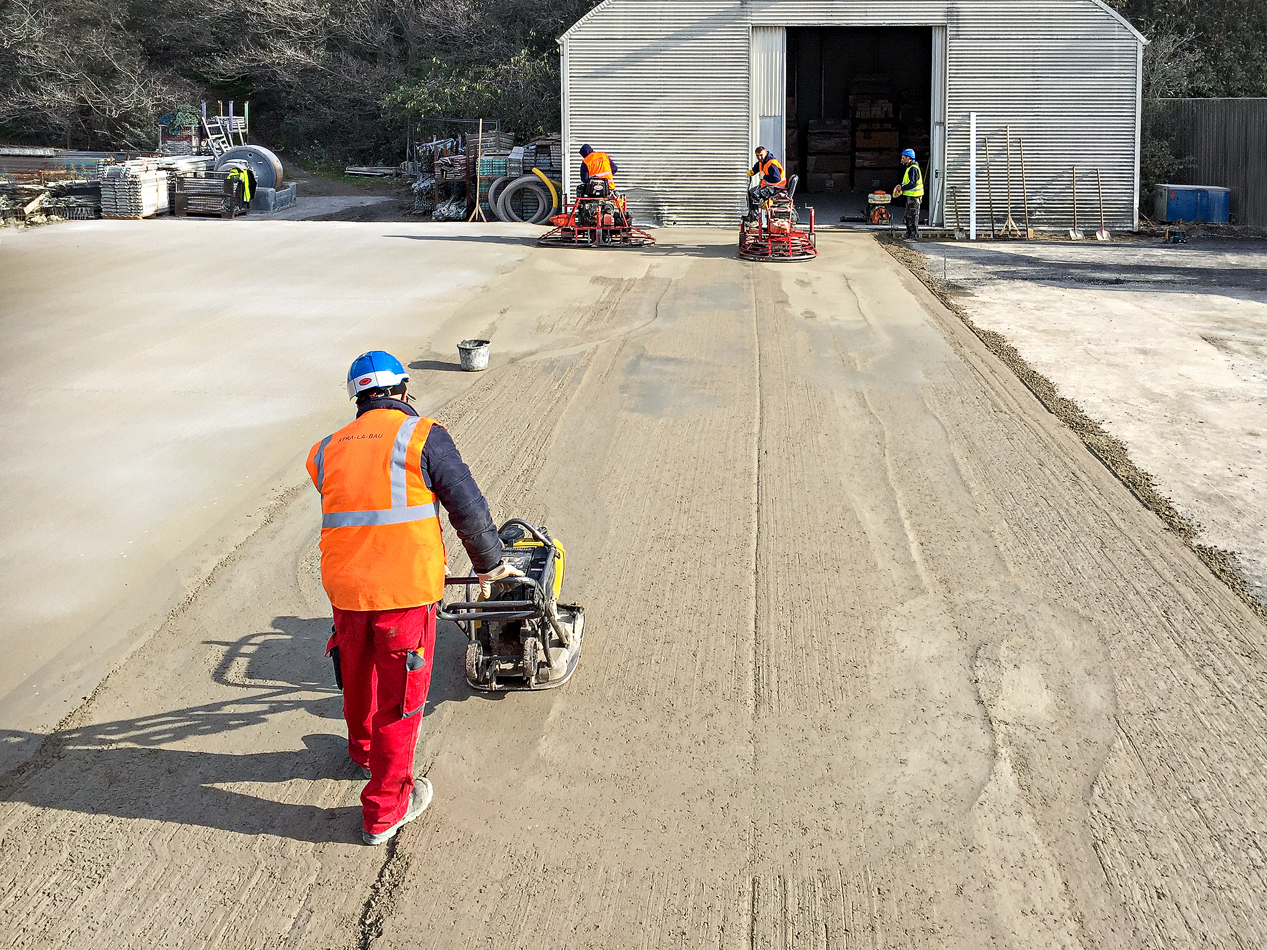 Hochbelastet Fahrbahnen und Stellflächen, die mit Asphalt- und Pflasteroberbauten nicht dauerhaft befestigt werden können, machen insbesondere bei Gewerbe-, Industrie- und Logistikbetrieben den Bau von Betonfahrbahnen fast zwingend erforderlich. Neben herkömmlichen hergestellten Betonflächen in Ortbetonbauweise bieten wir auch wirtschaftlich sehr interessante Walzbetonflächen und PCC-Flächen (Paver Compacted Concrete) an. Bei uns erhalten Sie Beratung, Planung und Bau - alles aus einer Hand. 