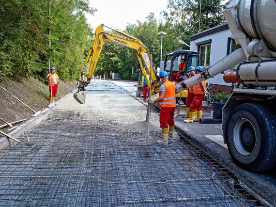 Hochbelastet Fahrbahnen und Stellflächen, die mit Asphalt- und Pflasteroberbauten nicht dauerhaft befestigt werden können, machen insbesondere bei Gewerbe-, Industrie- und Logistikbetrieben den Bau von Betonfahrbahnen fast zwingend erforderlich. Neben herkömmlichen hergestellten Betonflächen in Ortbetonbauweise bieten wir auch wirtschaftlich sehr interessante Walzbetonflächen und PCC-Flächen (Paver Compacted Concrete) an. Bei uns erhalten Sie Beratung, Planung und Bau - alles aus einer Hand. 